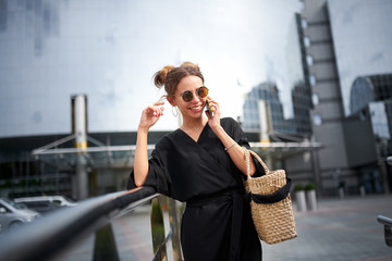 Woman in black dress and sunglasses talking on the phone