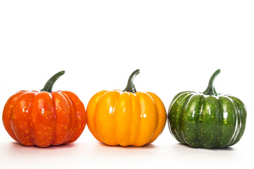 Three decorative artificial little pumpkins on a white background. Multi-colored vegetables of orange-yellow-green color for home decoration for the fall holiday, Halloluin