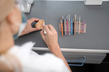 Dental technician using brushes to clean porcelain prosthesis.