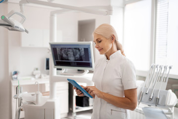 Obraz na płótnie Canvas Smiling dentist messaging her assistant asking about patients.