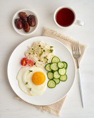Healthy breakfast - fried egg with cherry tomatoes and cucumber on light white background, fodmap dash diet, gluten free, top view closeup