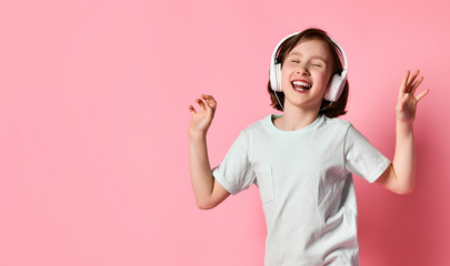 portrait of girl of music listens in white headphones, enjoying the pleasure of listening to music against a pink background