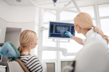 Dentist showing big picture of patients jaw x-ray.