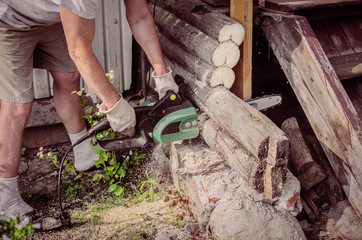 Sawing an old porch from a log with a chain electric saw