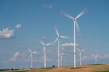 Wind turbines on the fields under a blue sky with some clouds