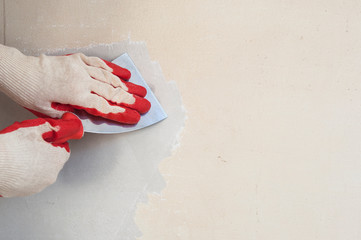 hand with a spatula cleans the wall from Wallpaper