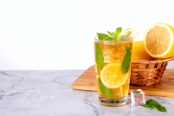 Glass of iced tea with mint and lemon on marble table. Cold drink.