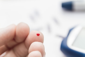 Man using lancet pen on finger to checking blood sugar level by blood glucose meter. Diabetes concept. Closeup, selective focus