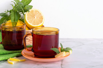 Glass of tea with mint and lemon on marble table.