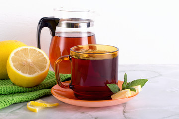 Glass of tea with mint and lemon on marble table.