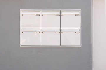 Graphic view of white mailboxes on a grey wall of a house