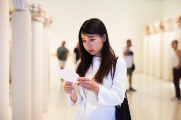 Chinese woman with guide looking at exhibition in museum of arts