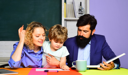 Home family schooling. Mathematics for kids. Schoolboy learning letters and numbers with parents. Parents teaching kid private lessons in math. Back to school. Home schooling. Parents helps child boy.