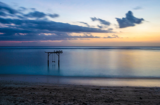 An empty swing on a gili travangan island with a stunning sunset.
