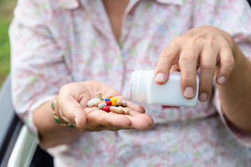 Closeup of hand senior woman medicine pills or capsules in hand,sick female patient taking,eating vitamin,antibiotic,painkiller,nutritional supplements,asian elderly woman,health care,medicine concept