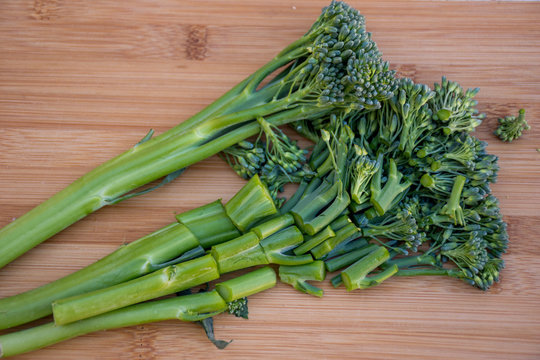 Bunch of fresh broccolini on a wooden board background cutted in pieces. Healthy eating. Cooking ingredient