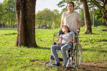 Sick child girl with cerebral palsy in wheelchair outdoor park or daughter suffering from...