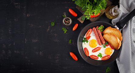 English breakfast - fried egg,  tomatoes, sausage,  and toasts. Banner. Top view, overhead