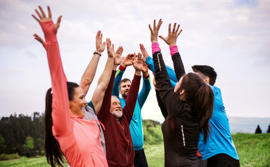 Large group of fit and active people resting after doing exercise in nature.