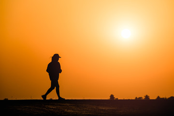 Silhouette woman running on sunset background