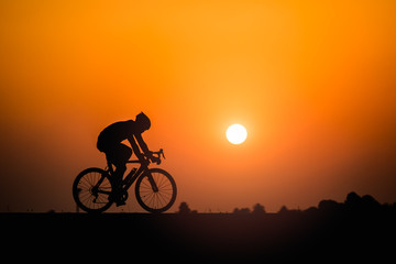 Obraz premium Silhouette man cycling on sunset background