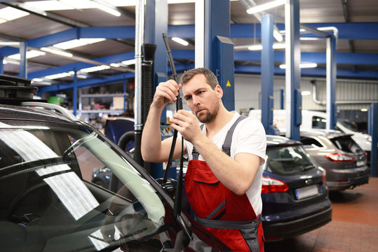 Austausch Scheibenwischer am Fahrzeug in einer Autowerkstatt durch professionellen Mechaniker // Replacement of windscreen wipers on the vehicle in a garage by a professional mechanic