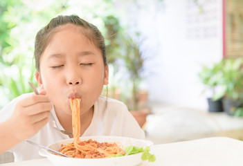 girl enjoy eating spaghetti with pork sauce,