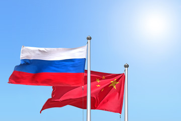 russia and china national flag waving against sunny blue sky side view of natural color of russian federation and people republic of china state symbols isolated for design mockup copy space template