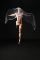 Fototapeta na wymiar Naked gymnast jumping with transparent cloth
