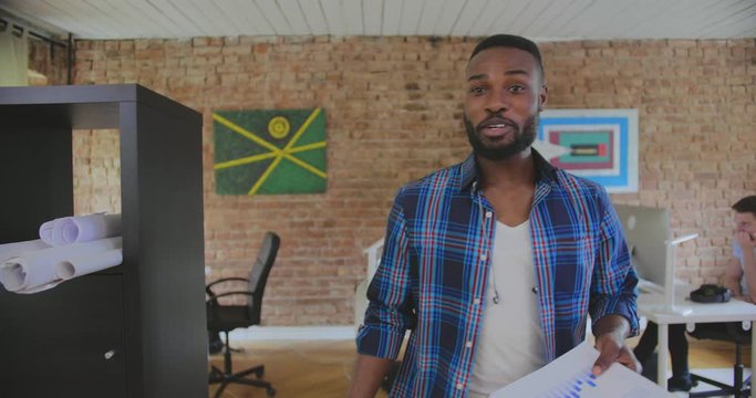Cheerful black teamleader comes to his multiracial colleagues, they hug and celebrate high growth rates