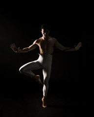 Male dancer standing against black background with extended hands