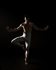 Obraz premium Male dancer standing against black background with extended hands