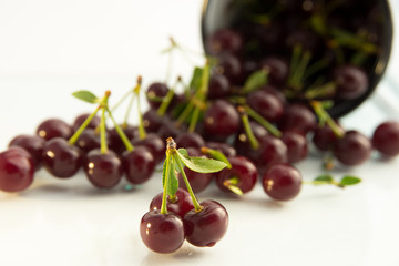 berries ripe red cherries scattered from the iron clubs and are on a white background, berries, fresh cherries with leaf and branch