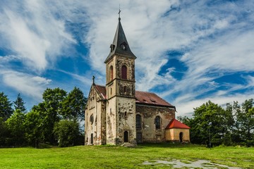Fototapeta na wymiar Krasikov, Kokasice / Czech Republic - August 9 2019: View of the old church of Mary Magdalene. Bright sunny summer day with blue sky and white clouds, green grass and trees.