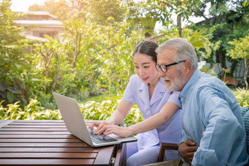 Caregiver assist senoir eldery man typing using notebook laptop computer connect to Internet