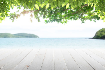 Fototapeta premium Old empty wooden table and palm leaves with party on beach blurred background in the daytime.