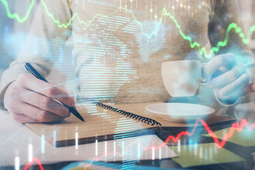 Forex chart hologram on hand taking notes background. Concept of analysis. Double exposure