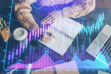Forex graph on hand taking notes background. Concept of research. Double exposure