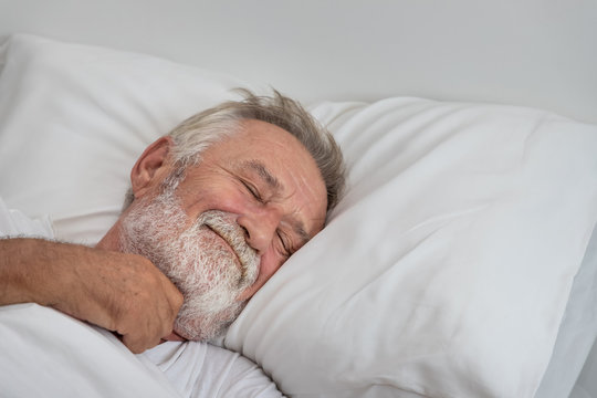 Senior elderly man sleeping happily with white blanket in bedroom