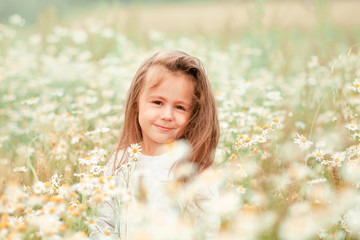 Cute little girl in big camomile meadow.