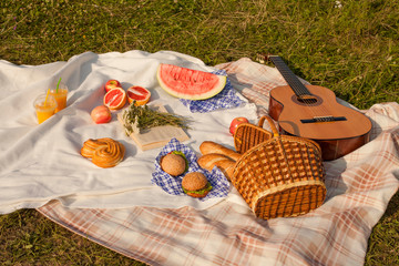 Lunch in the park on the green grass. Summer sunny day and picnic basket