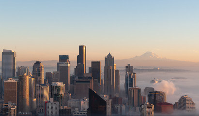 Partially immersed in the mist caming from Elliott Bay, this panoramic view of Seattle at sunset, was taken in a cold autumn day, with blue sky and the Mount Rainier visible on the background.