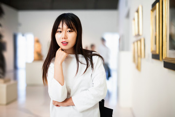 Fototapeta premium Chinese female visitor looking at artwork painting in the museum indoors