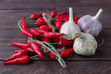 red pepper and heads of garlic in a basket on a dark wooden background