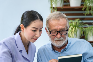 Senior elderly man reading book with nurse in garden