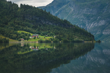 Fototapeta na wymiar Shore of vang lake in Norway, beautiful summer landscape, mountains and clouds are reflected in the water
