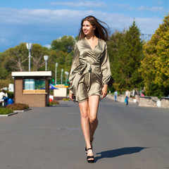 Young beautiful woman in green dress walking on the summer street