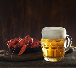 glass of beer and boiled crayfish wooden background