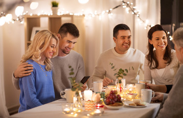 celebration, holidays and people concept - happy family with smartphone having tea party at home