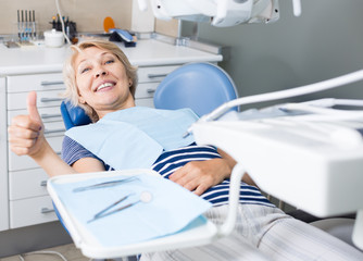 Satisfied woman visiting dentist giving thumbs up